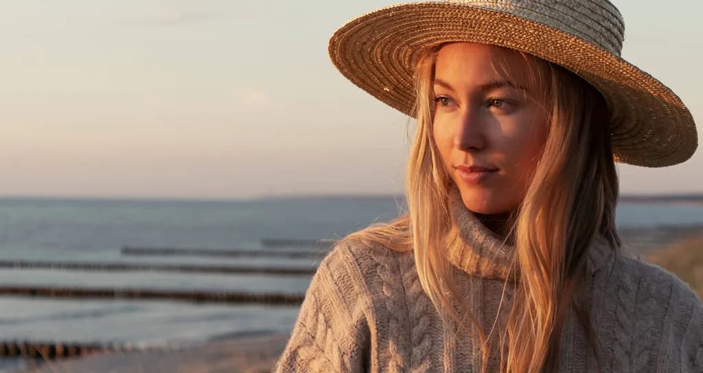 Žena sa slamnatim šeširom na obali mora u suton